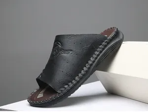 Détail d'une sandale en cuir noir avec logo embossé et semelle cousue à la main