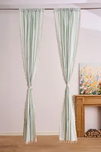 Detail view of light green and white striped cotton linen curtains with cream tassel fringe