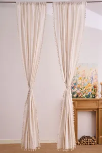 Dettaglio di tende in cotone e lino crema con nappe e motivo a righe per interni
