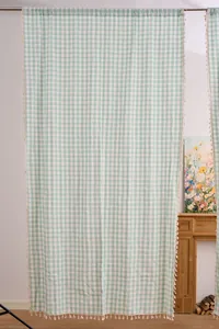 Sage green gingham curtain with handmade tassels in a French country setting