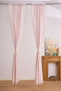 Detailed view of pink striped curtains with tassels hung in a cozy home fireplace setting