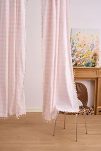 Detail of pink striped curtains with delicate tassel fringe in a home setting