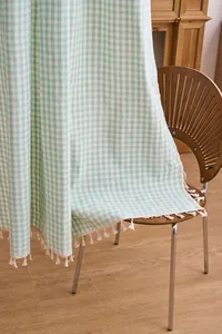 Detailansicht des salbeigrünen Gingham-Vorhangs mit weißen dekorativen Quasten