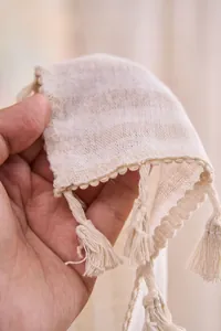 Primo piano di tenda in cotone e lino crema con dettagli di nappe a frangia.