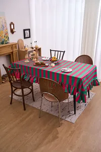 Detailed view of a red and green striped velvet tablecloth with elegant ruffled edges.