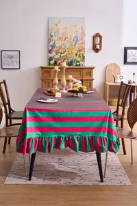 Detail view of pink and green striped velvet tablecloth with elegant ruffled edges.