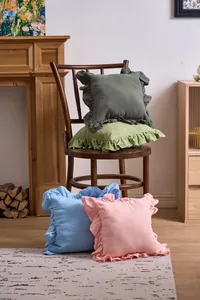 French ruffle throw pillow covers in various pastel colors on a vintage wooden chair