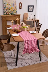 Red and white checkered table runner with ruffled edges displayed on a wooden table
