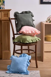 Close-up of elegant French ruffled solid color pillowcases stacked on a rustic wooden chair.