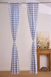 Vintage blue and white striped cotton linen curtains with tassel trim in a cozy room