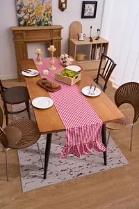 Detail view of a red and white checkered table runner with ruffled edges in a cozy dining room.