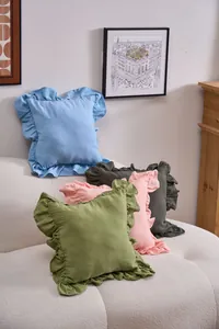 Four colorful French ruffle pillowcases arranged on a stylish cream sofa