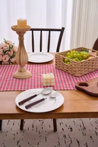 Red checkered table runner with ruffled edges displayed on a rustic wooden dining table