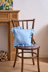 Detail view of light blue French ruffle pillowcase on a vintage wooden chair