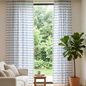 Vintage blue and white striped cotton linen curtains with tassels in a sunlit living room