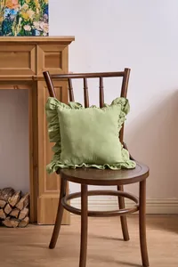 Detail view of a green French style ruffled cushion cover on a rustic wooden chair