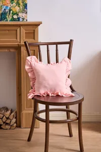 Detailed view of a soft pink French ruffle edge pillowcase on a vintage wooden chair