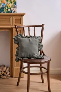 Detail of French ruffle edge pillow cover in solid olive green on a classic wooden chair