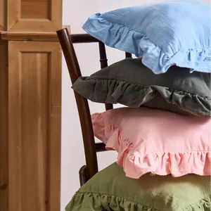 Solid color French style ruffle pillowcases stacked on a wooden chair for home decor.