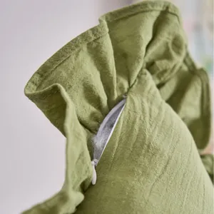 Close-up of green French ruffled pillowcase with hidden zipper and linen texture
