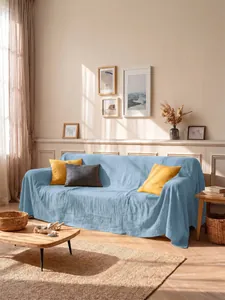 Copridivano in cotone lavato azzurro drappeggiato in un soggiorno luminoso e molto moderno