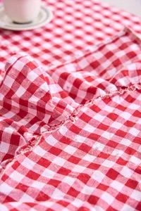 Macro detail of red and white gingham tablecloth fabric with delicate ruffled edge