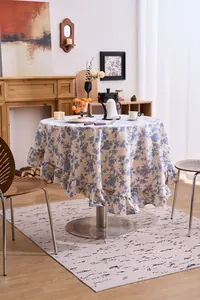 Detail of French vintage blue floral round tablecloth with elegant ruffled edges.