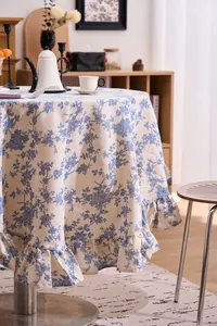 Detailed view of a vintage French floral round tablecloth with elegant ruffled edges.