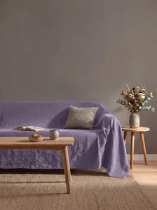 Elegante copridivano in cotone lavato viola mostrato in un soggiorno minimalista