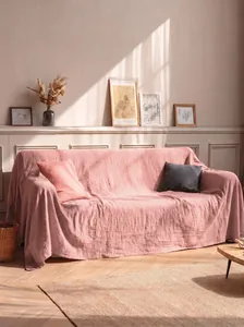 Elegante copridivano in cotone lavato rosa drappeggiato in una stanza soleggiata e accogliente