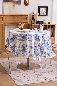 Vintage French floral round tablecloth with ruffled edge in a cozy indoor dining room.
