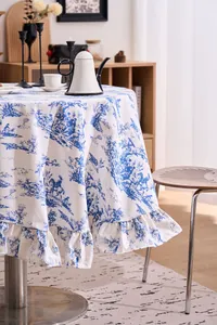 Elegant close-up of a vintage blue French toile print round tablecloth with ruffled edges