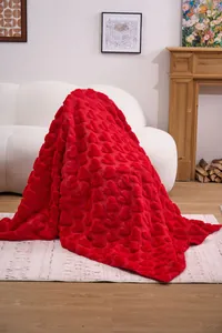Detailed view of soft red plush blanket with embossed heart pattern in home setting.