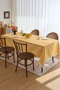 Yellow gingham checkered tablecloth with delicate white lace trim in a cozy dining setting