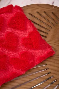 Detailed macro shot showing the soft texture of a red plush blanket with embossed hearts