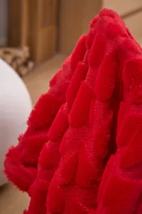 Close-up of red plush blanket featuring a carved leaf pattern texture for cozy naps