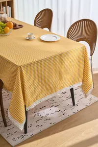 Yellow and white gingham tablecloth featuring delicate white lace trim in a home setting