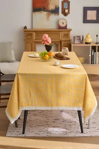Detail of yellow gingham tablecloth with delicate white lace trim in rustic style