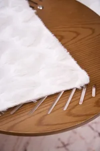 Macro view of white embossed plush faux fur blanket texture on wooden table