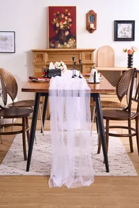 White sheer tulle fabric draped elegantly on a wooden dining table for event decor