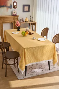 Detailed view of yellow gingham tablecloth with delicate white lace border in dining room.