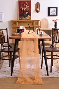 Elegant apricot tulle fabric draped over a wooden dining table for event decoration