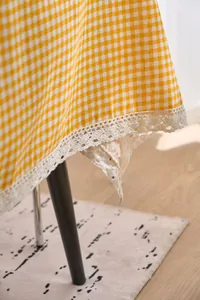 Close-up detail of yellow checkered tablecloth with elegant white lace border