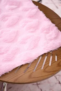Close-up of pink plush blanket featuring elegant carved floral pattern texture