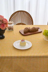 Detailed macro view of a yellow gingham check tablecloth in a cozy pastoral tea setting.