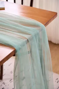 Close-up of sage green tulle drape showing mesh texture and soft drapery on a table.