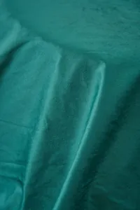 Detailed macro shot of soft emerald green velvet fabric texture on a warm fleece blanket