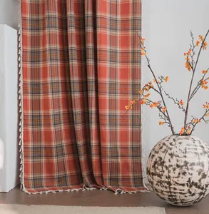 Dettaglio della tenda semi-oscurante a quadri arancioni con frange a nappa eleganti