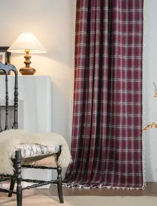 Detailed view of red plaid curtain with white tassels in a cozy rustic interior