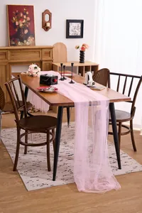 Sheer pink tulle table runner draped on a wooden table for wedding decor